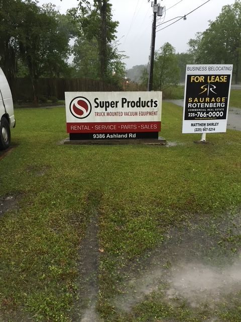 Super Products roadside sign in rainy grassy lot, with smaller fuel and repair sign beside it
