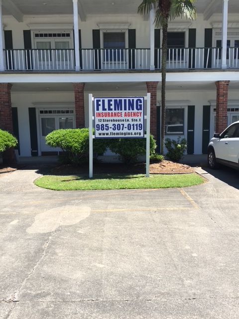 Fleming sign outside a two-story building with balconies and parked cars in front
