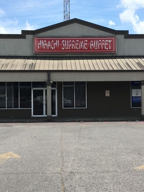 Storefront with a red “Kandi Supreme Buffet” sign above dark windows and a parking lot in front