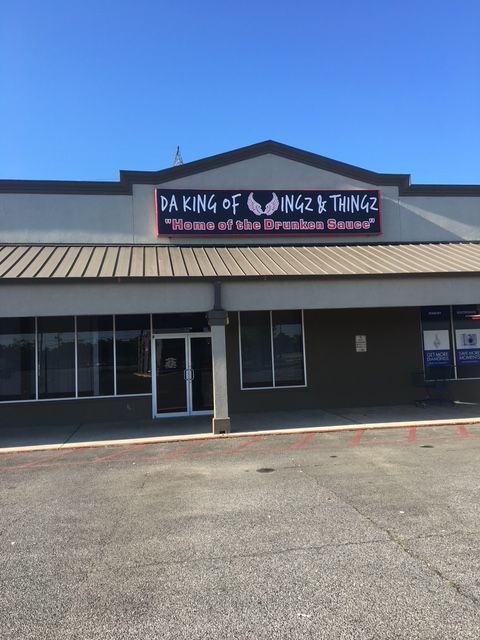 Storefront of “King of Niz & Thingz” with a black facade and blue sky above