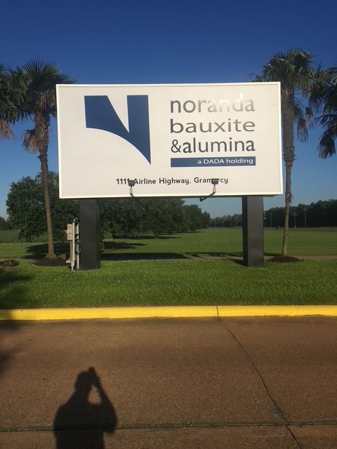 Noranda Bauxite alumina sign on a roadside lawn in bright sunlight