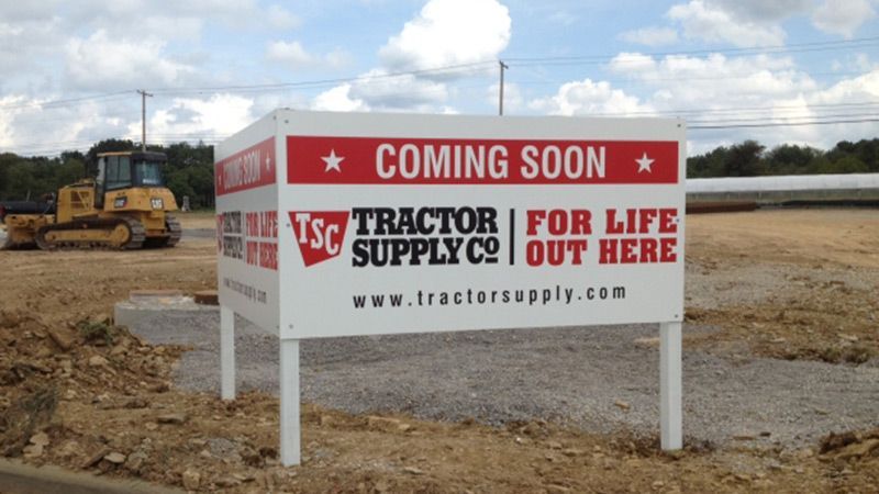 Tractor Supply Co. “Coming Soon” sign at a construction site with a bulldozer in the background