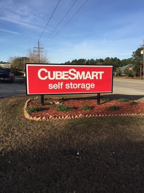 CubeSmart self storage sign on a roadside, red with white lettering, under a blue sky.