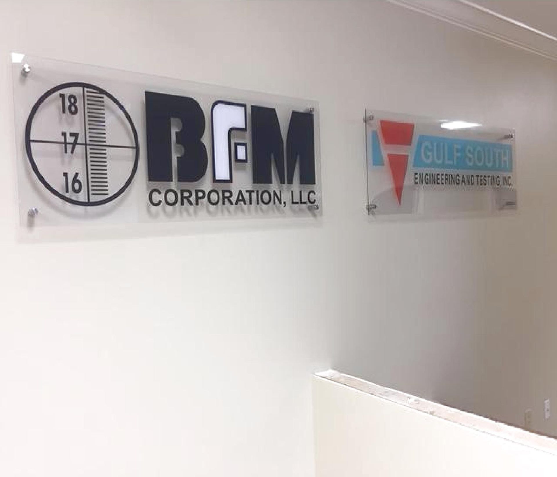 Office wall with BFM Corporation LLC and Gulf South company signs above a stair railing