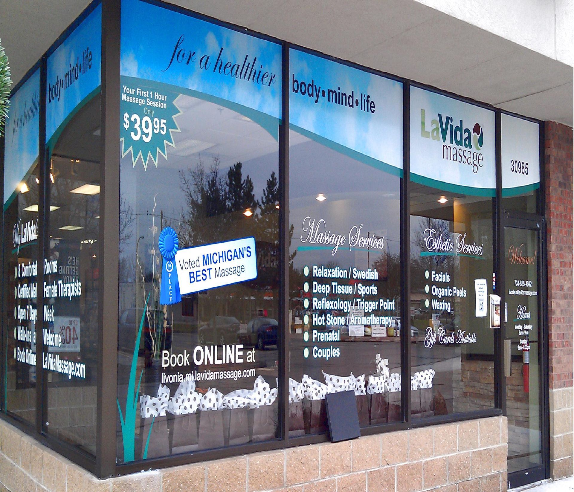 Storefront with large windows, blue accents, and signage advertising online booking and services.