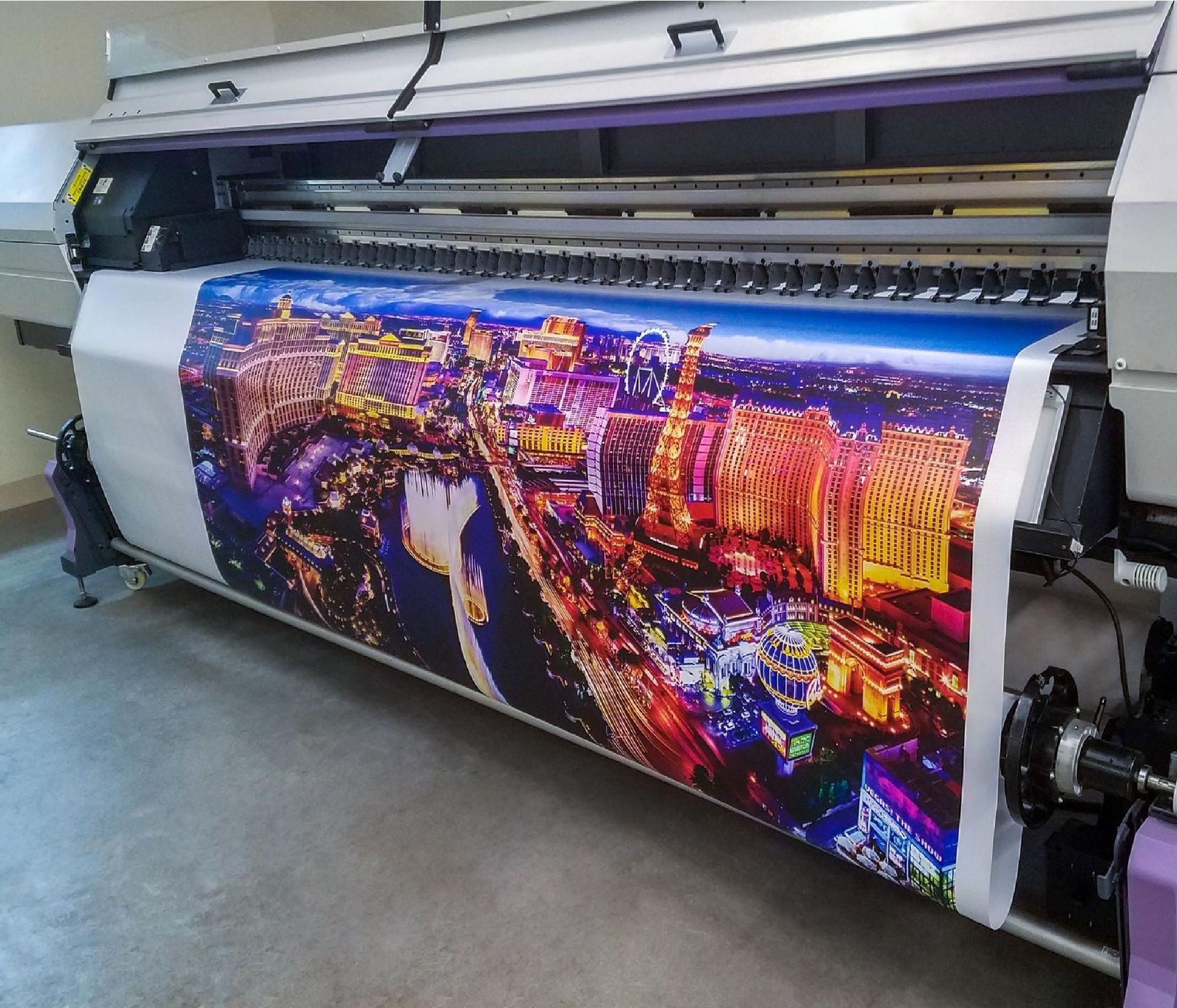 Large-format printer producing a vivid nighttime cityscape banner in a workshop