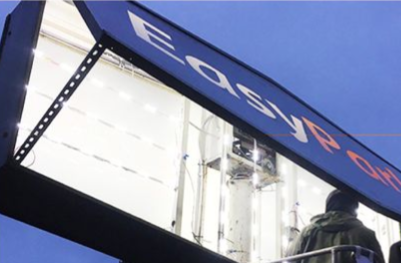 Blue E-ZPass sign on a toll booth at dusk, with bright lights underneath