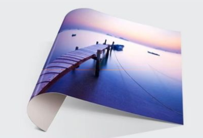 Curved glossy photo print of a dock extending into calm blue water at sunset