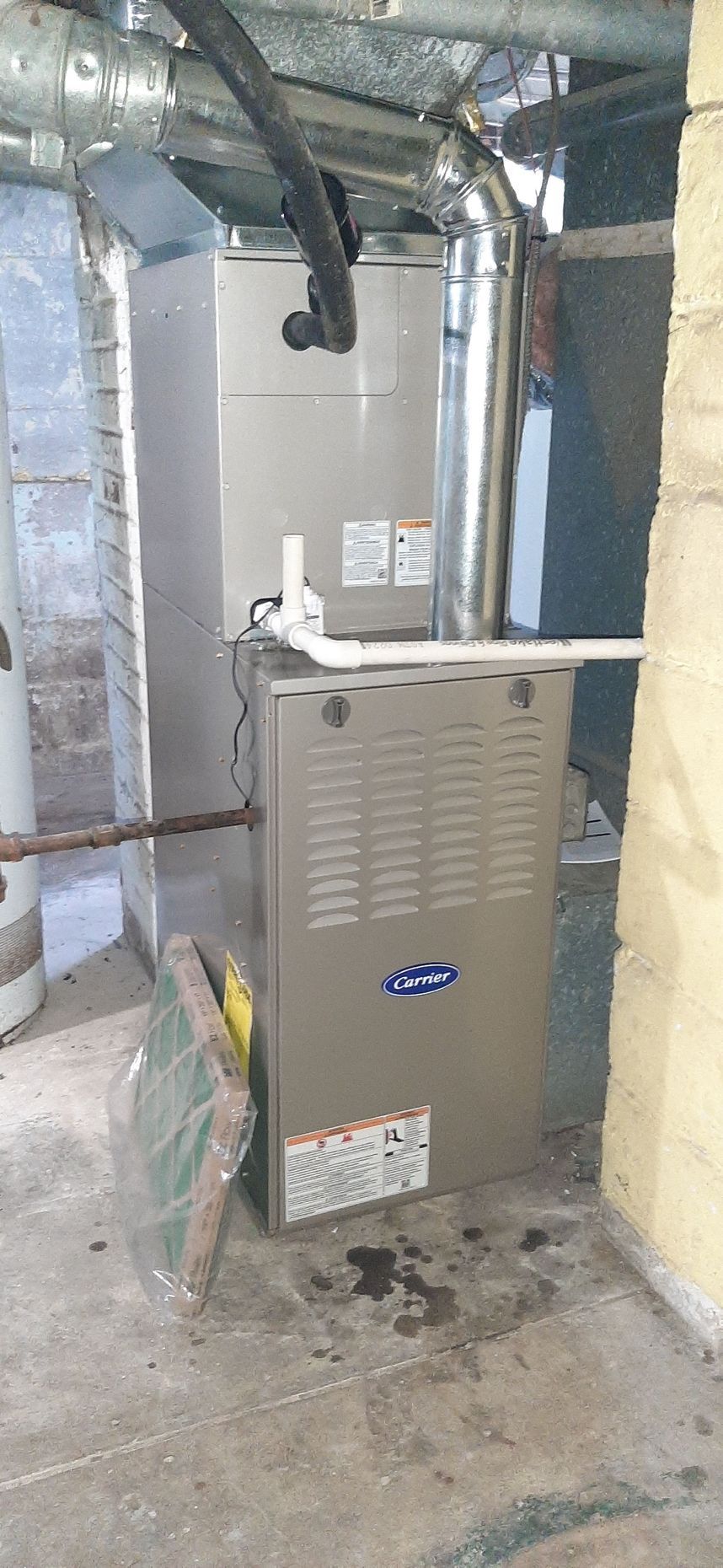 Furnace in a basement. The unit is silver and labeled