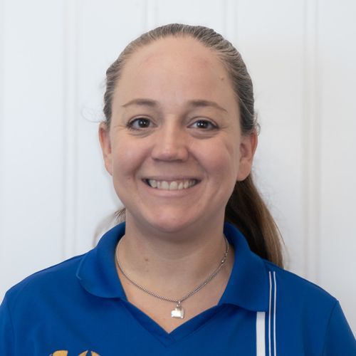 Woman in blue polo smiling, standing in front of a garage.