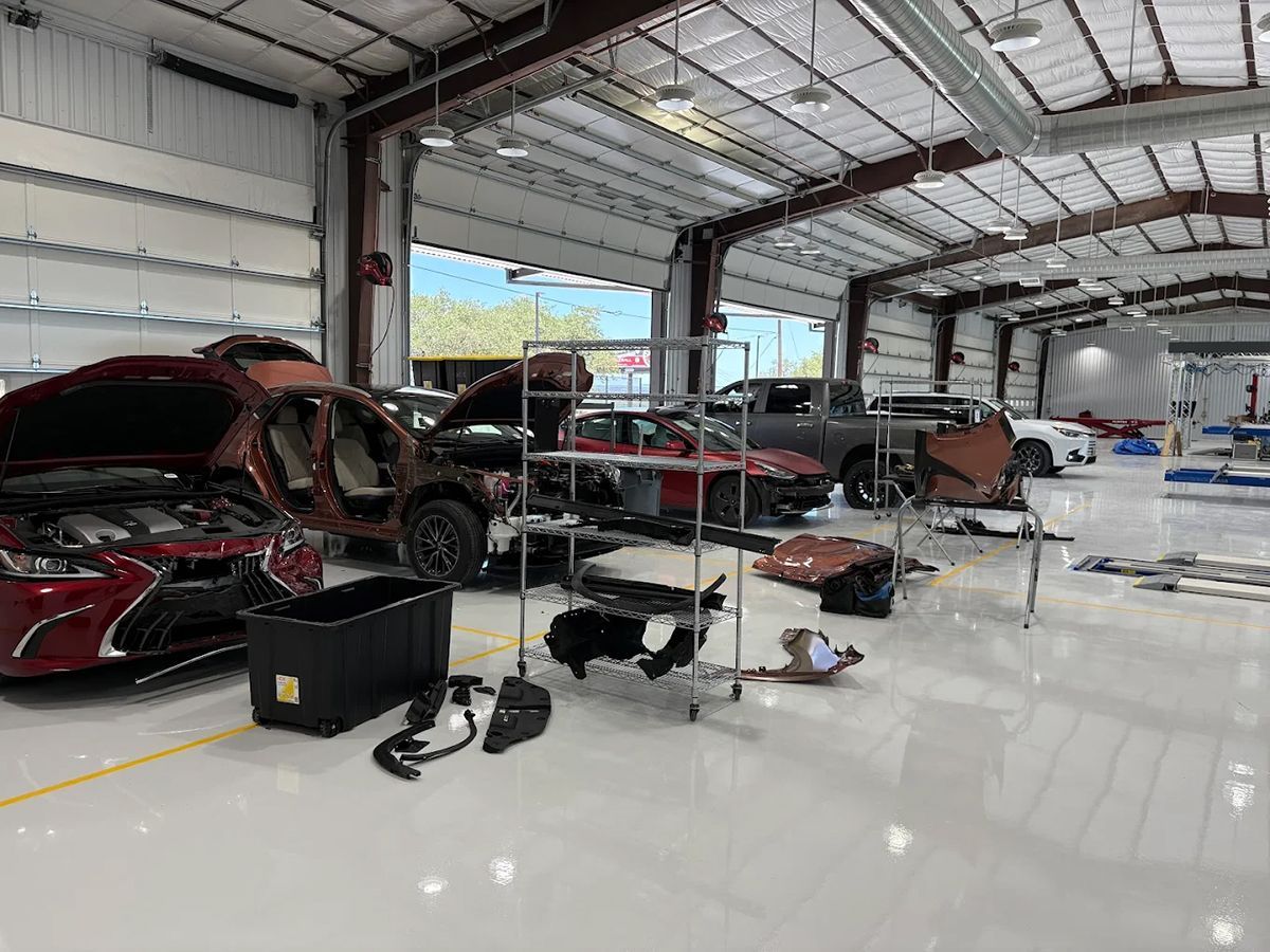 Interior of an auto repair shop with several partially disassembled vehicles.