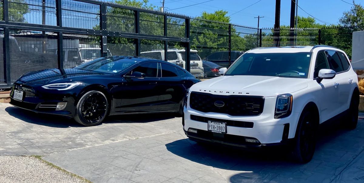 Black Tesla sedan and white Kia Telluride SUV parked in a lot.