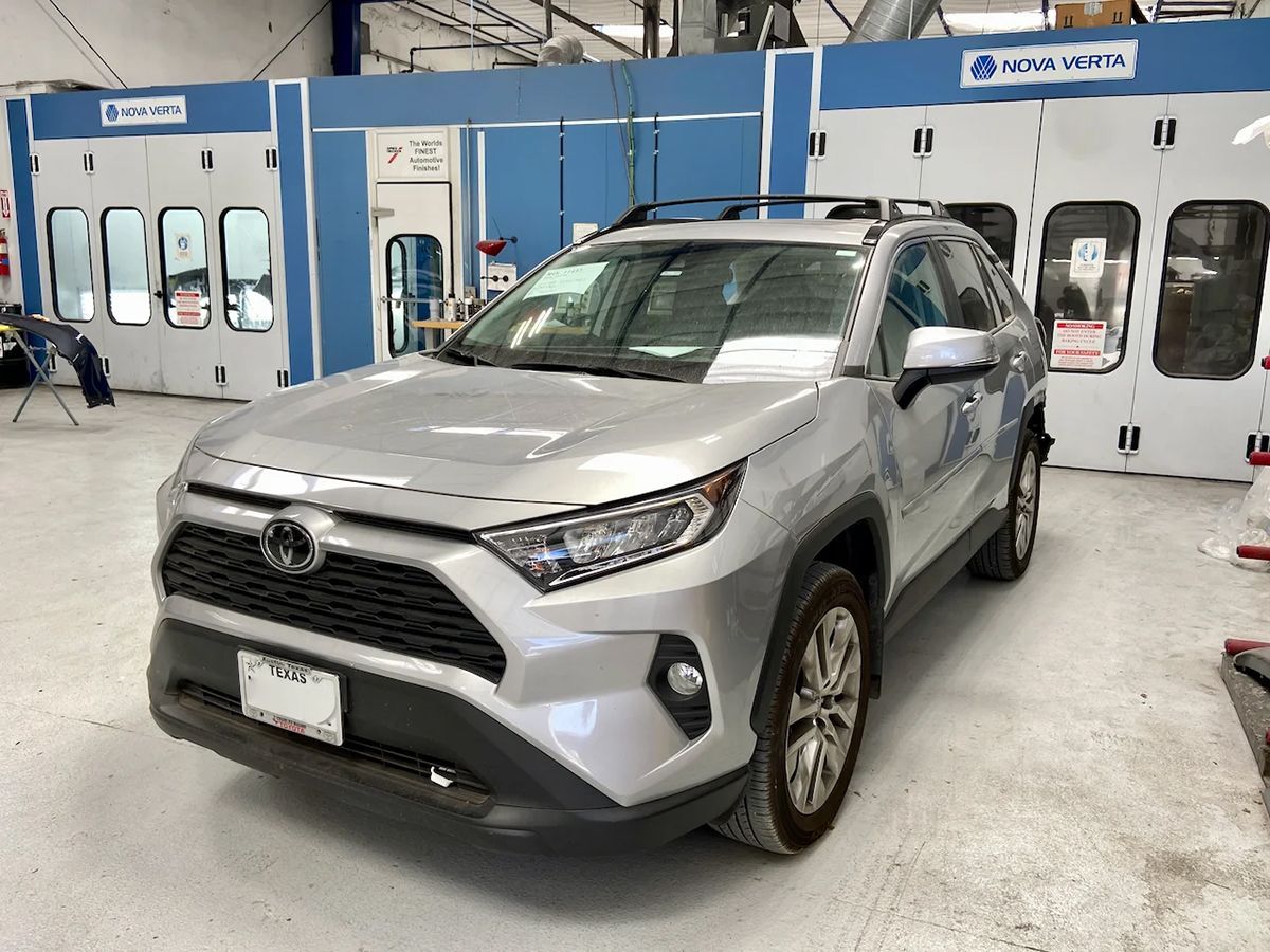 Silver Toyota RAV4 in a body shop, in front of paint booths.