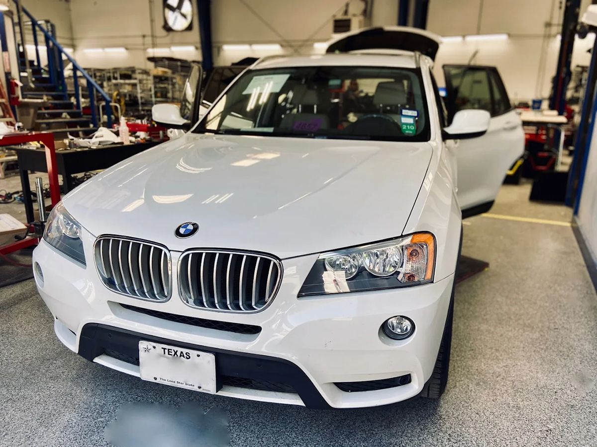 White BMW X3 SUV in a garage, doors open.
