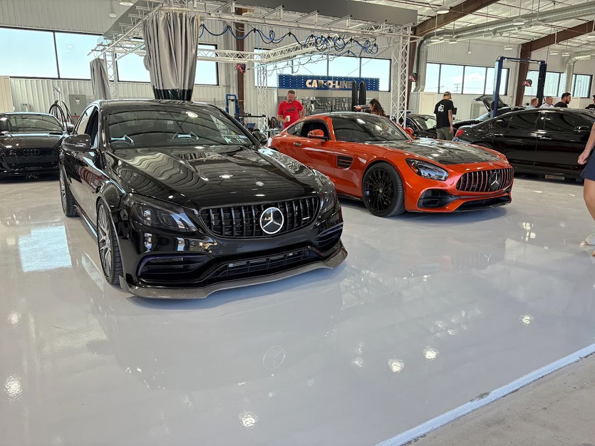 Black and orange sports cars on display at an event. Cars are parked on a glossy floor, in a well-lit space.