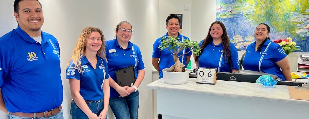 A group of people wearing blue shirts posing near a counter with a plant.