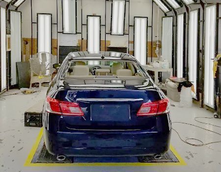 Dark blue car in a bright garage with overhead and side lights.