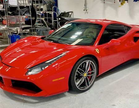 Red Ferrari sports car parked inside a garage.