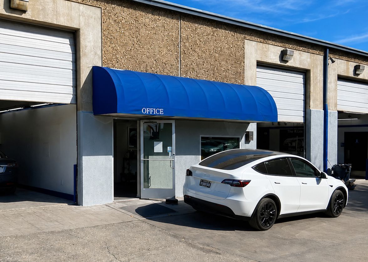 White car parked in front of a building with a blue awning and garage doors