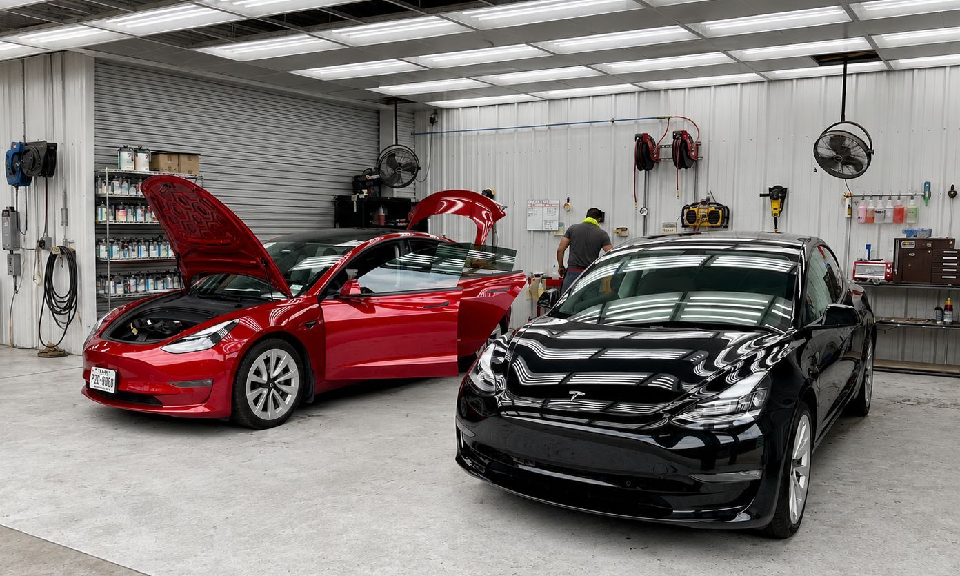 Red and black cars in a garage, with the red car’s hood open.