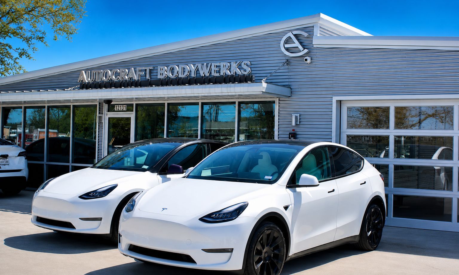Two white Tesla cars parked outside a Lexus dealership on a sunny day