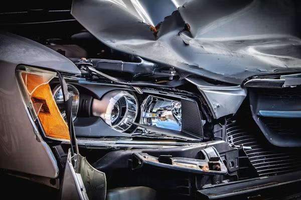 Close-up of a car’s front end with severe collision damage and crumpled hood.