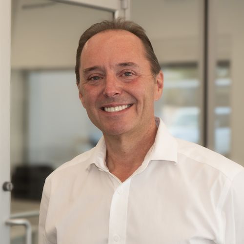 Smiling man in a white shirt standing in a bright office setting