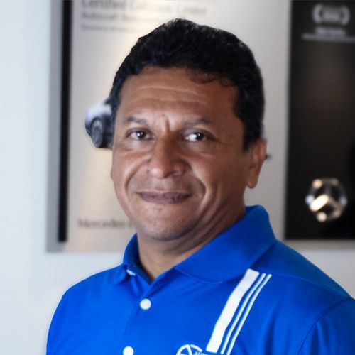 Man in a blue polo shirt smiling indoors against a blurred office-like background