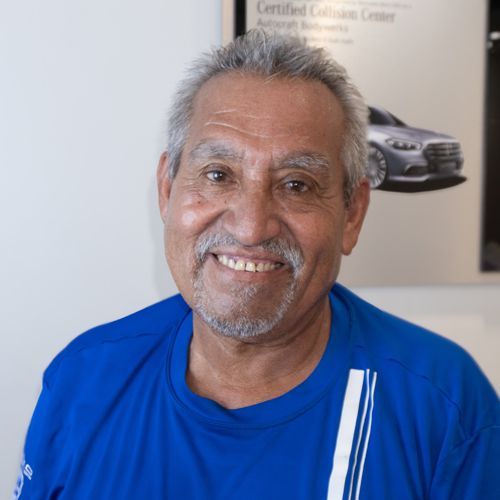 Smiling man in a blue shirt standing indoors near a car poster