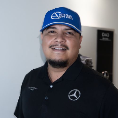 Smiling man in a blue cap and black polo shirt standing indoors
