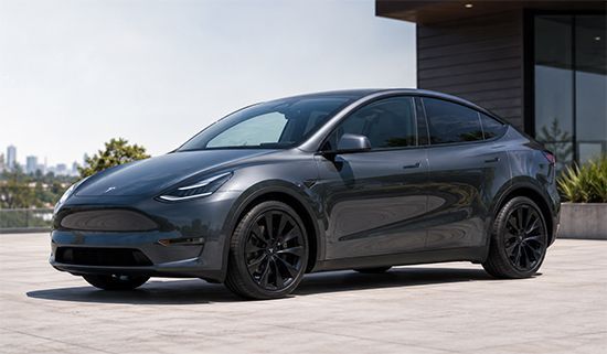 Black Tesla sedan parked outdoors in front of a modern building.