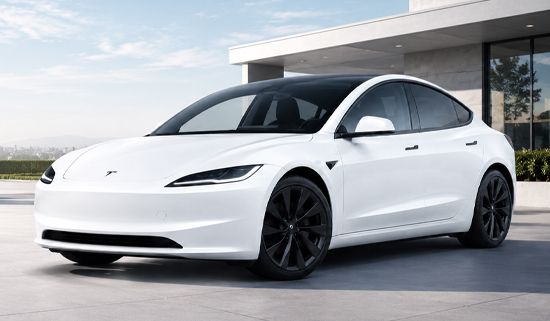 White Tesla sedan parked outdoors in front of a modern building