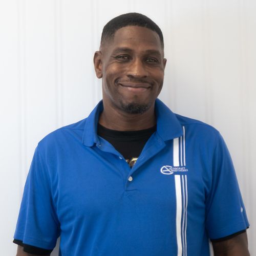 Smiling man in a blue polo shirt standing against a plain white background