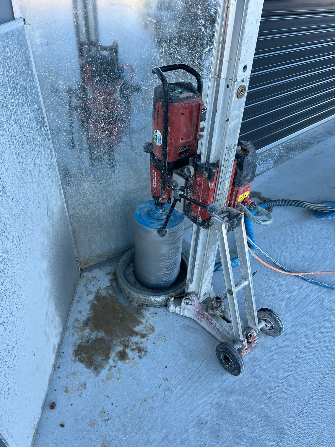 A red and white machine is sitting on a concrete floor next to a wall.