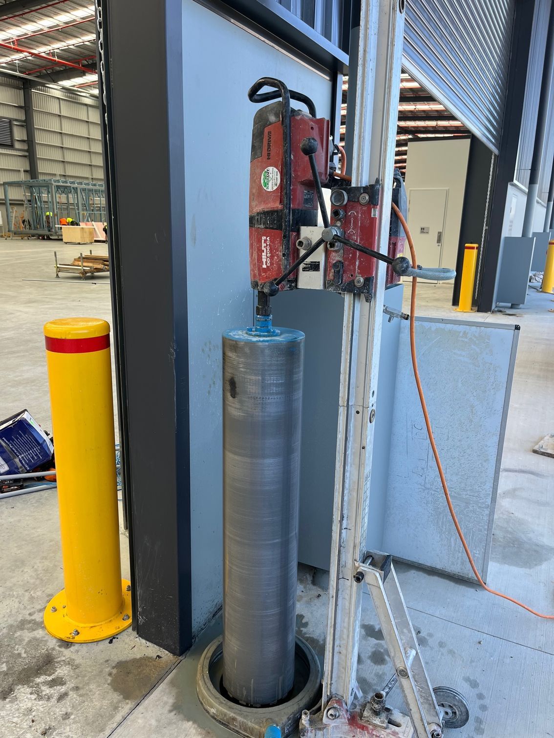 A machine is cutting a hole in a wall in a warehouse.