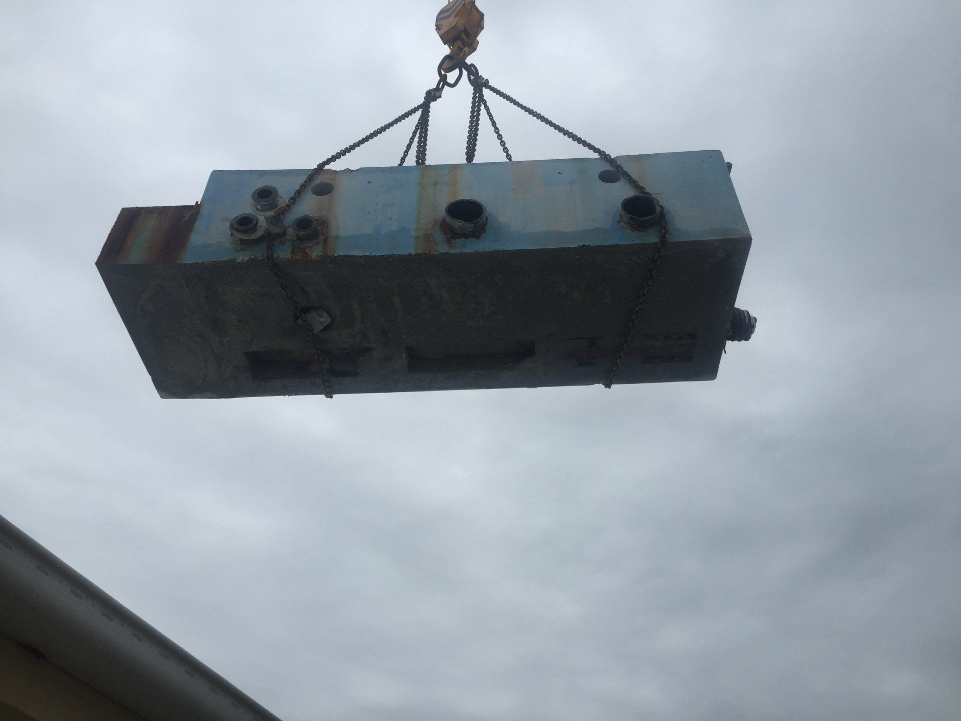 A large piece of metal is being lifted by a crane