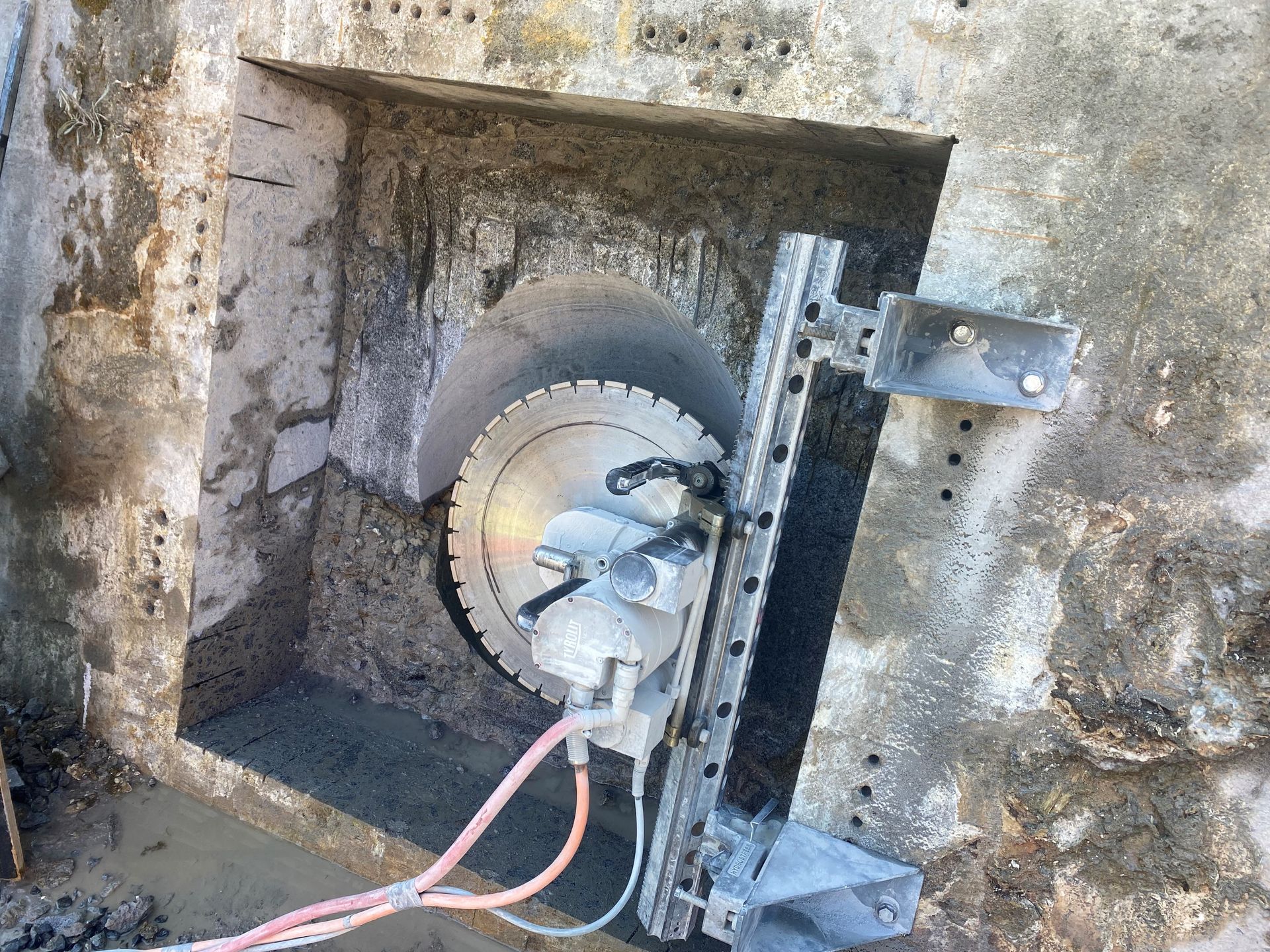 A machine is cutting a hole in a concrete wall.