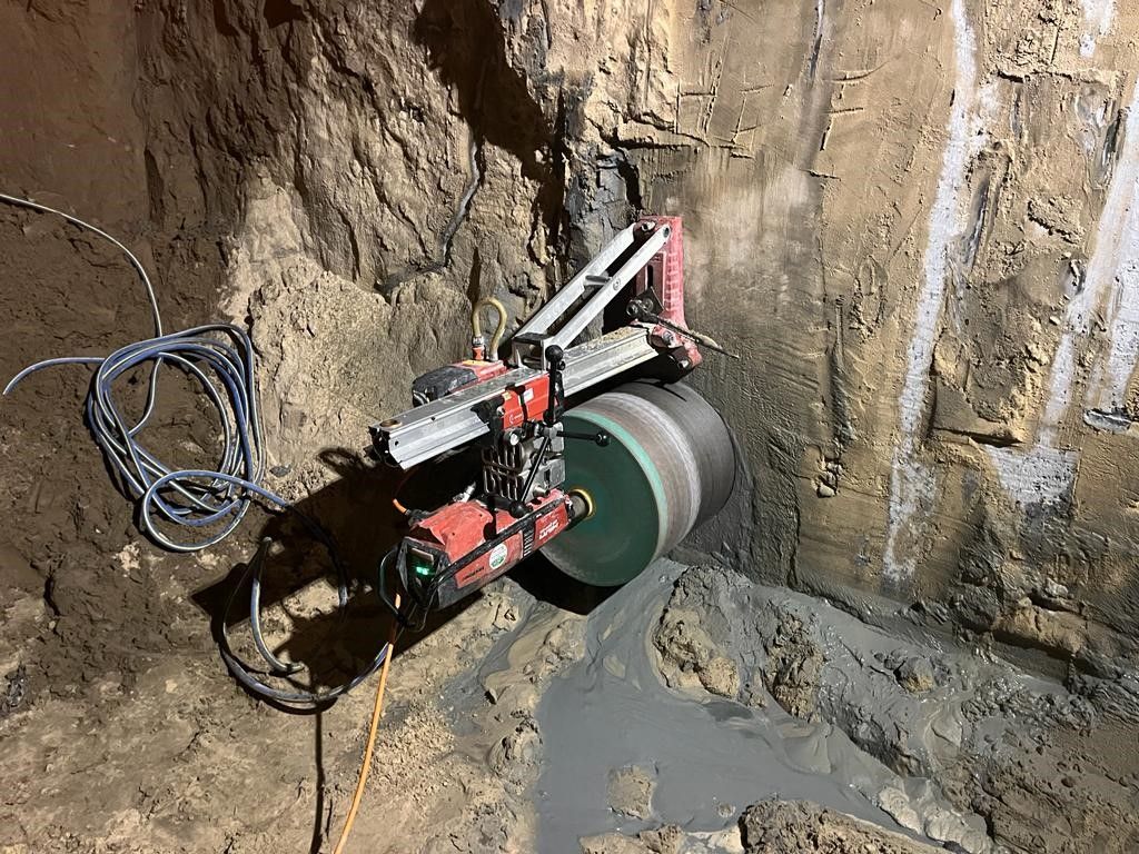 A machine is cutting a hole in the ground in a cave.