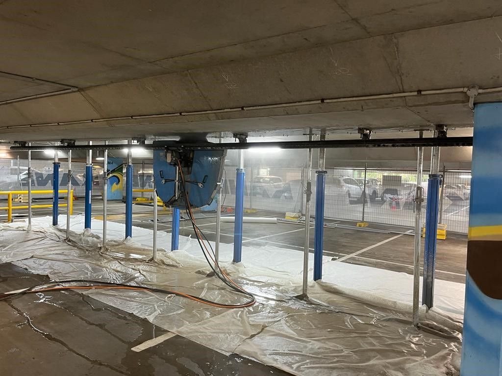 A parking garage with a lot of water coming out of the ceiling.