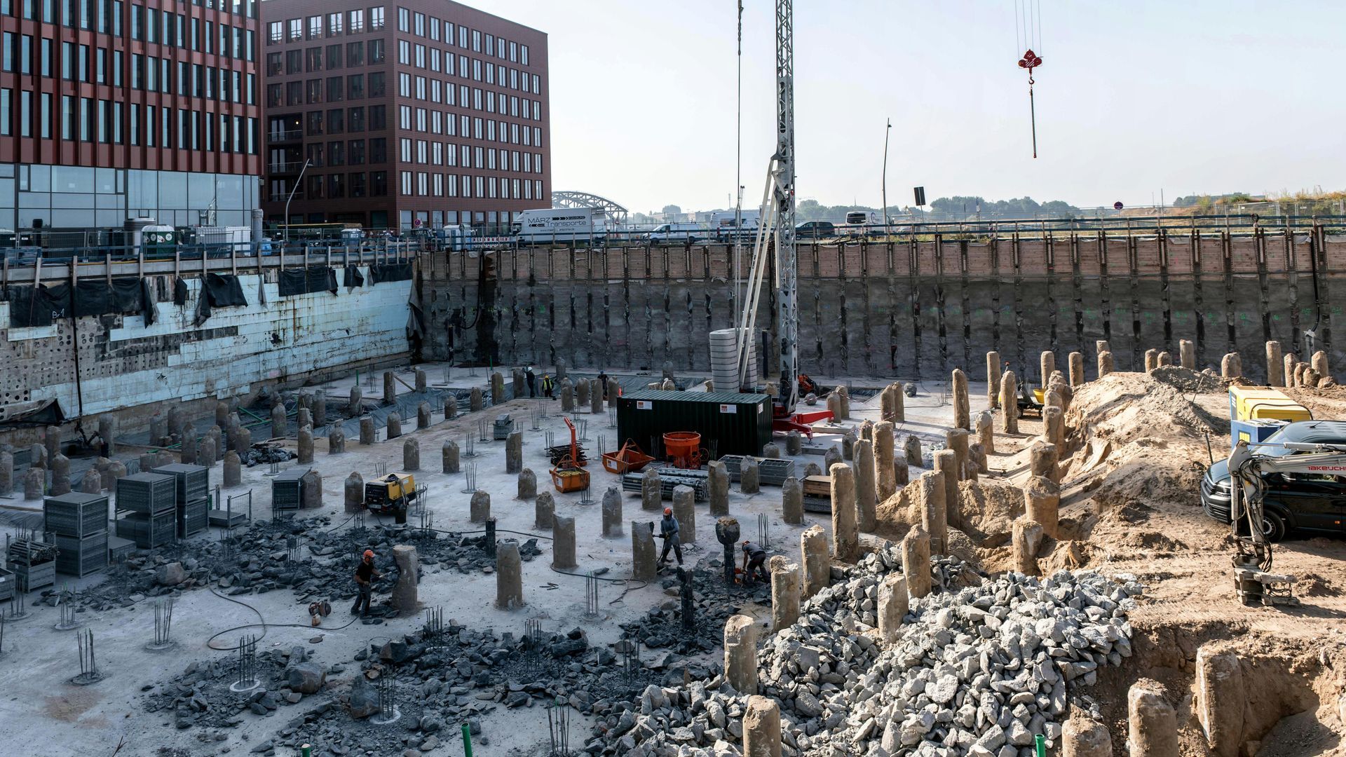 A construction site with a lot of rocks and a large building in the background.