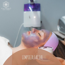 Una mujer está recibiendo un tratamiento facial con una mascarilla morada en la cara.