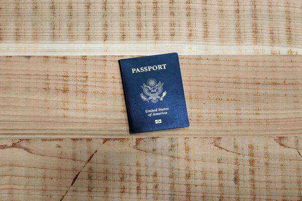 A blue passport is sitting on a wooden table.