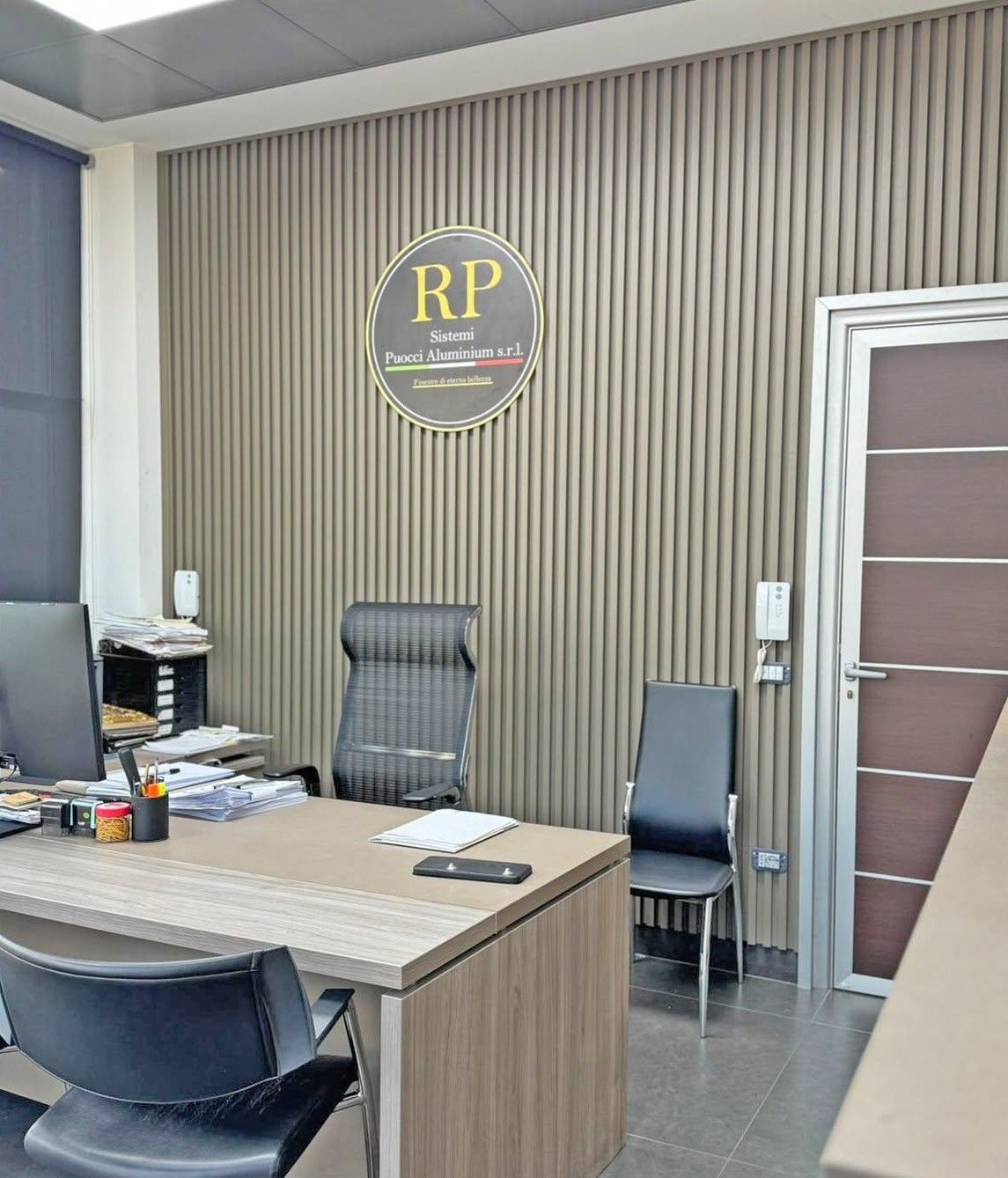 Ufficio moderno con scrivania, sedie e parete rivestita in legno con il logo 