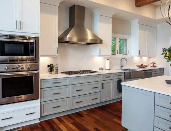 Modern white kitchen with stainless steel appliances, gray cabinets, and a wood floor
