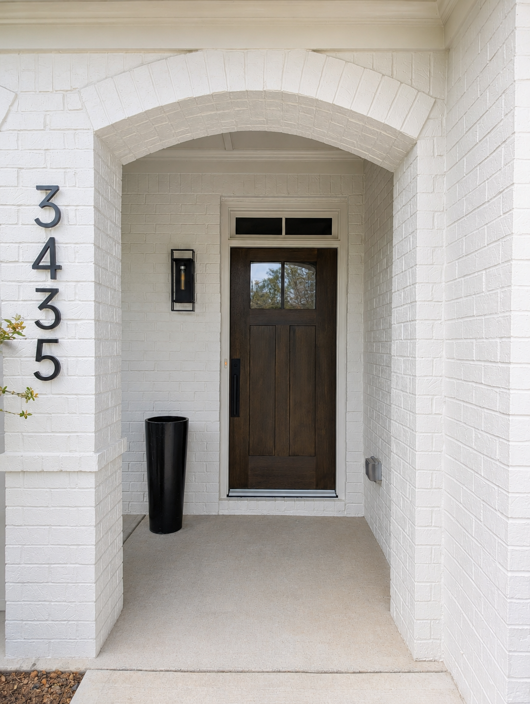 Front porch entry with white brick walls, dark wood door, and house number 3435 beside the doorway