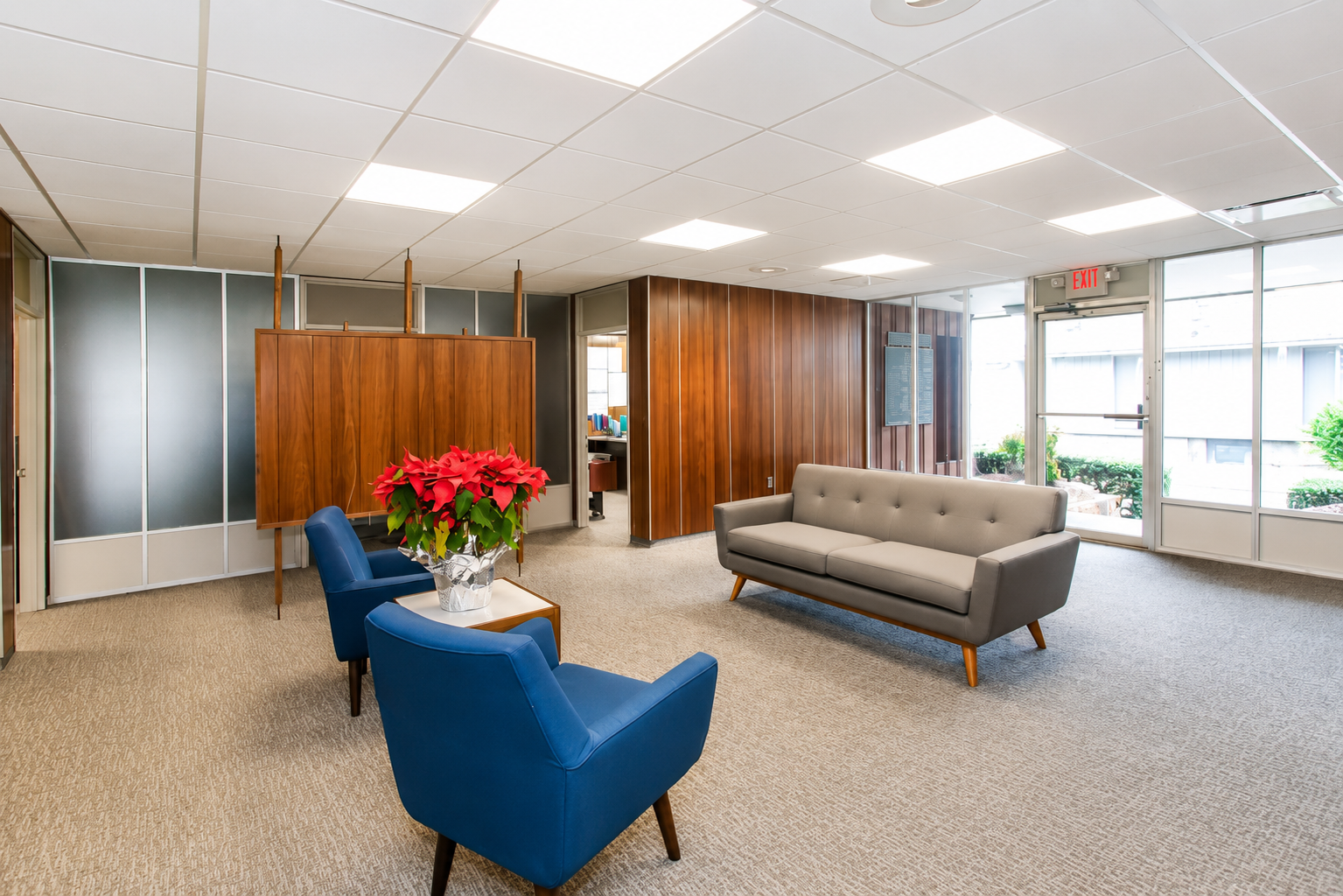 Modern office lobby with blue chairs, gray sofa, wood partition, and red flowers