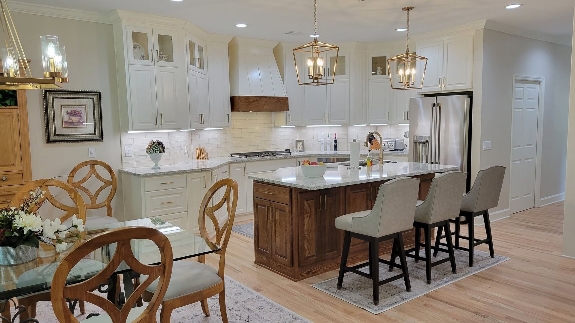 Bright modern kitchen with white cabinets, island seating, and adjacent round dining table