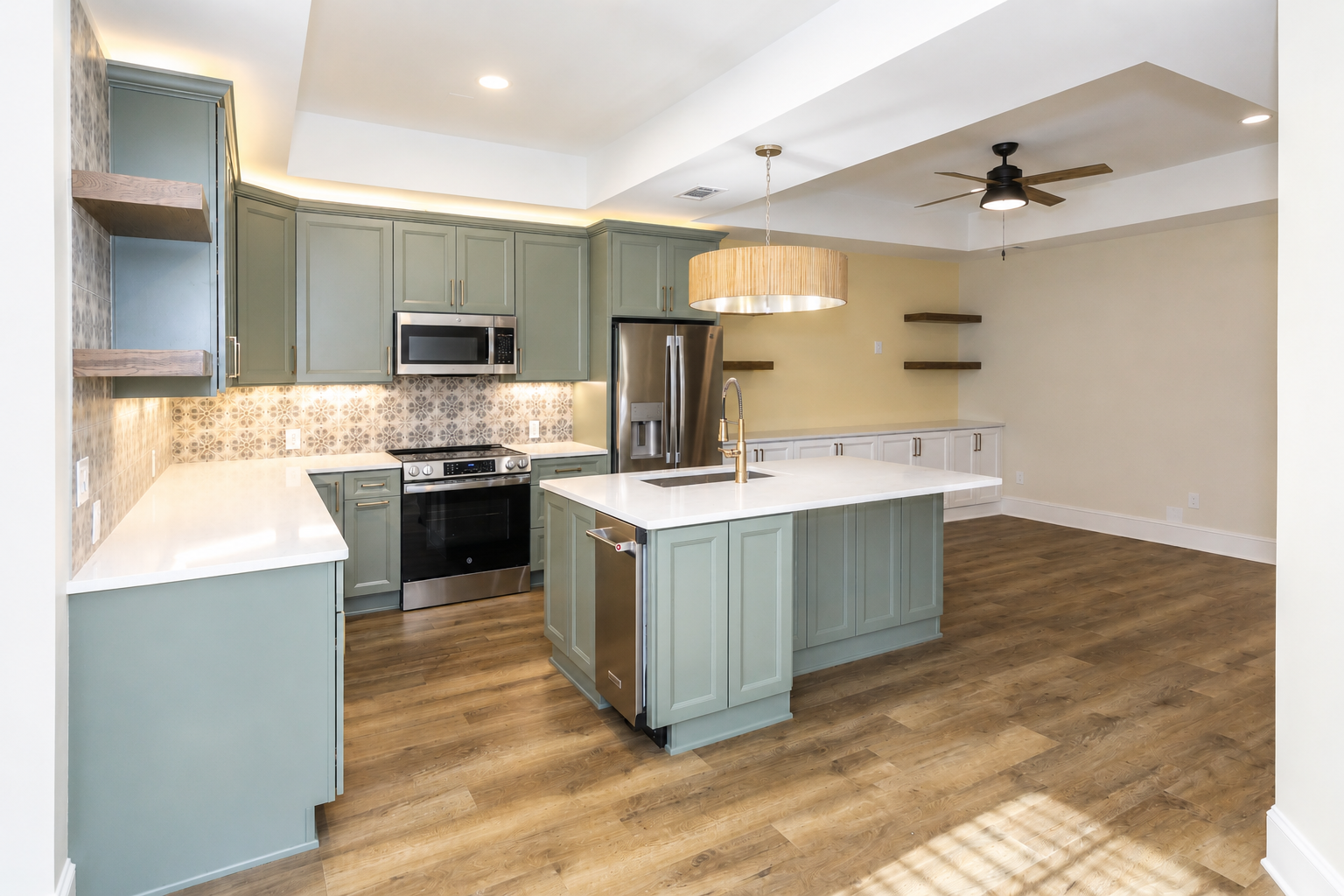 Modern open-plan kitchen with gray cabinets, white island, and wood floors adjoining an empty living area