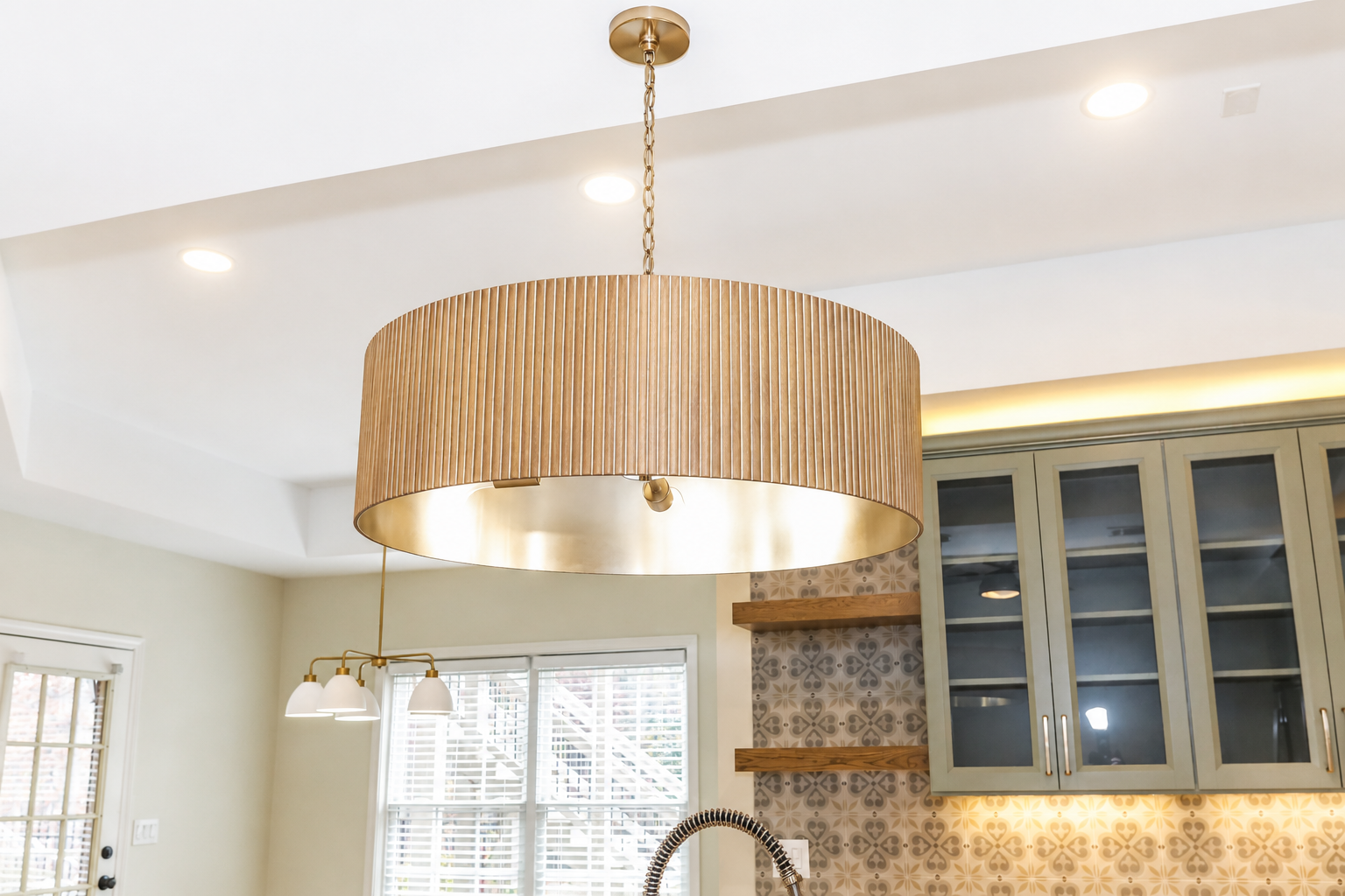 Kitchen with a large wood-and-gold pendant light above a blue cabinet and patterned backsplash