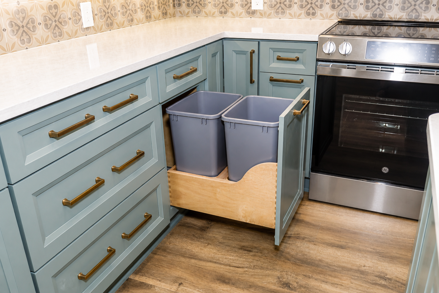 Kitchen with blue cabinets, stainless oven, and pull-out recycling bins beside the counter